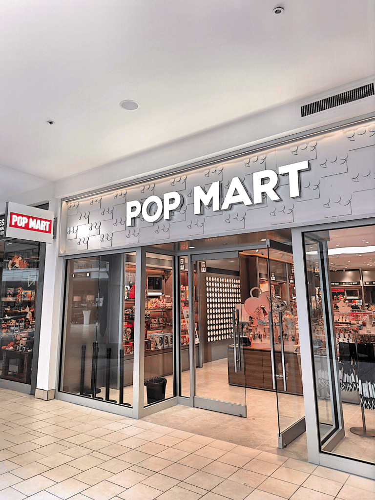 Exterior photo of Pop Mart retail store with Labubu merchandise seen in glass window.
